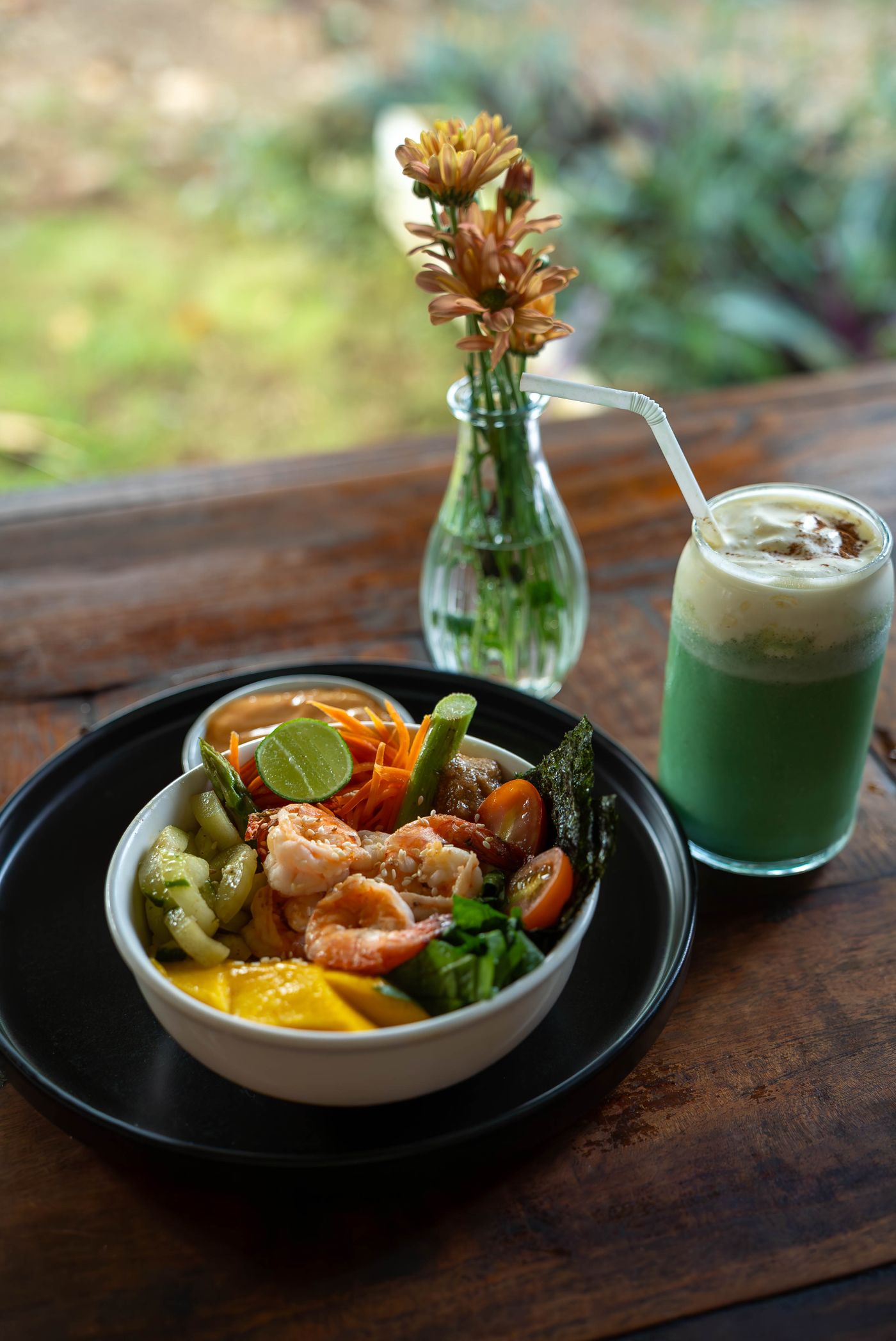 A fresh, colorful meal bowl with shrimp, vegetables, and a green smoothie